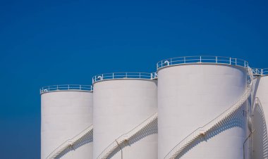 Yakıt tankları endüstri arka planı, petrol rafinerisi alanındaki beyaz depolama tankı mavi gökyüzüne karşı, endüstriyel ham petrol kimyası üretim arkaplanı