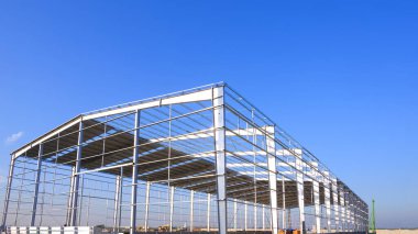 İnşaat alanındaki büyük fabrika deposu endüstriyel yapı yapısı mavi gökyüzü arkaplanına karşı, düşük açılı kopya alanı manzaralı