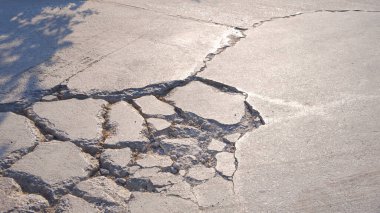 Yüzeyinde çatlak çizgi dokusu olan kötü hasar görmüş eski beton sokak arka planı.