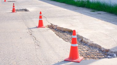 Yol güvenliği ve yan görüş için sokak yüzeyindeki eski hasarlı yolu güçlendirilmiş çelik inşaat demirleri ve trafik konileri ile yenile