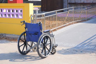 Açık hava tuvaletinin rampa alanının önündeki tekerlekli sandalye.