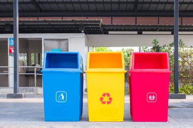 Benzin istasyonundaki umumi tuvaletin önündeki kaldırımda çöp kutularını ayıran çok renkli atık seti.