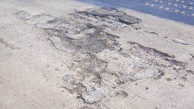 Beton yol yüzeyinde kırık ve çökmüş dokusu olan eski kötü hasar görmüş sokak arka planı.