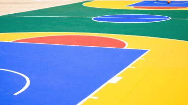 Açık hava basketbol sahası. Renkli desenli ve beton zemin yüzeyinde beyaz çizgili. Spor alanı arka planı, yan görüş.