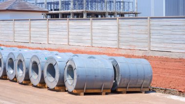 Yerdeki galvanize çelik bobinler endüstriyel fabrika şantiyesinin önünde duvar tesisatı için, fotokopi alanı ile yan görüş