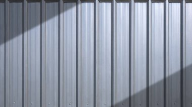 Depo binasının arka planında, yüzeyde ışık ve gölge çapraz desenli gri kıvrımlı çelik dış duvar.
