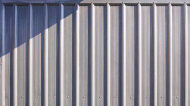 Gray corrugated metal exterior warehouse building  wall background with light and shadow on surface