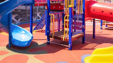 Anaokulunun çocuk parkı alanındaki kauçuk zeminde çocuk parkı ekipmanlarıyla renkli slaytlar