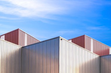 Fabrika endüstriyel yapı arka plan tasarımı, gümüş ve kahverengi alüminyum kaplı sanayi deposu mavi gökyüzüne karşı metal cephe, modern minimal stil geometrik dış mimari