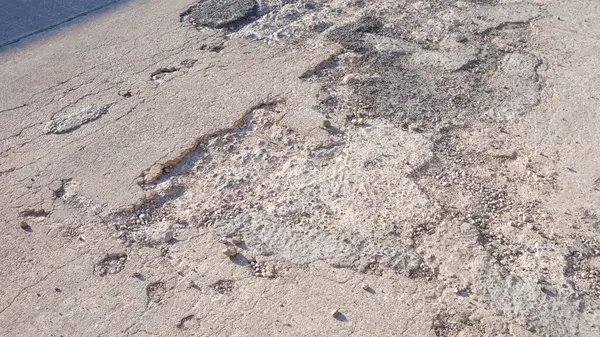 Eski ağır hasarlı beton yol arka planında sokak yüzeyinde kırık ve çökme dokusu var.