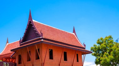 Tayland geleneksel ahşap evi ve yeşil ağaçlı gable çatısı açık gökyüzü arka planına karşı