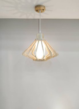 Modern asılı lamba ve geometrik ahşap kafes beyaz tavanda aydınlatma ve gri duvar oturma odası, ön manzara ve dikey çerçeve