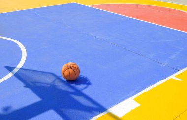 Basketbol sahası basketbol sahasında, ortaokulda beton bahçe zemininde, spor sahasının arka planında rengarenk çizgiler var.