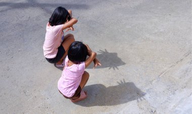 İki Asyalı kadın çocuk sokak zemininde gölge gibi görünmeye çalışıyor. Kore 'den gelen kedi gölgesi eğilimi sosyal medyada çok popüler.