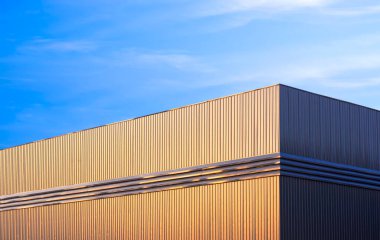 Gri alüminyum üzerinde altın güneş ışığı olan depo fabrikası inşaatı sabah vakti mavi gündoğumu gökyüzü arkaplanına karşı çelik duvarla çevrili, düşük açılı ve fotokopi alanı ile perspektif kenarlı.