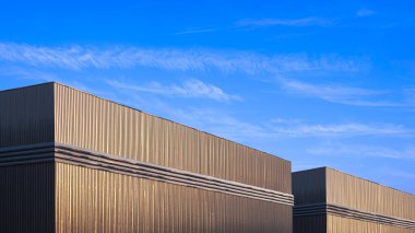 Siyah alüminyum kıvrımlı çelik duvarda havalandırması olan iki depo fabrika binası mavi gökyüzü arka planına karşı alçak açı ve fotokopi alanı ile perspektif yan görünümü