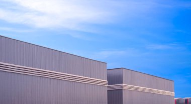 Fabrika deposu sanayi binaları. Gri alüminyum kaplamalı havalandırması var. Mavi gökyüzü arka planına dayanan metal duvar.