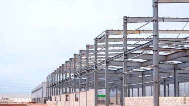 İnşaat alanındaki metal fabrikasının yapısı endüstri yerleşim alanındaki gri gökyüzü arka planına karşı, kopya alanı olan perspektif yan görünümü