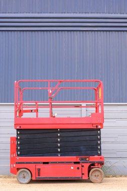 Depodaki fabrika inşaatı alanının önündeki beton duvarın yanında elektrik iskelesi ve fotokopi alanı olan dikey çerçeve.