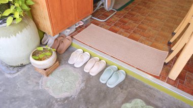 Pastel kauçuk sandaletler düzgün bir şekilde beton zemine dizilmiş eski evdeki fayans döşeme, yüksek açı ve fotokopi alanı.