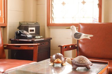 Cam masadaki dekoratif hayvan oyuncakları deri koltuklar ve telefon tuşları, ahşap evin köşesindeki ahşap dolabın kaset radyosu antika tarzı.