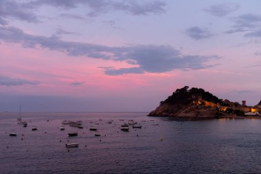 İspanya 'nın Tossa de Mar üzerinde gün batımının güzel renkleri denizin sakin sularını yansıtır.