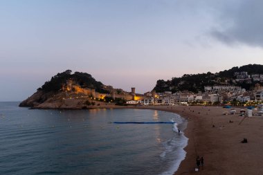 İspanya 'nın Tossa de Mar üzerinde gün batımının güzel renkleri denizin sakin sularını yansıtır.
