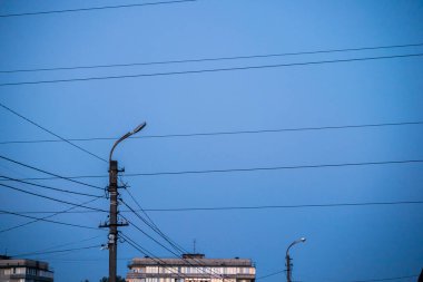 Mavi gökyüzü ve apartmanların arka planında elektrik hattı var..