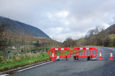 Turuncu ve beyaz bariyerler Cumbria, İngiltere 'de fırtınadan sonra kapalı bir yol olduğunu gösteriyor..