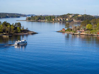Stockholm Takımadaları 'nın sakin sularında süzülen küçük bir feribotun yüksek açılı görüntüsü. İsveç' in mavi denizinde, yemyeşil, ağaçlık adalarla çevrili.. 