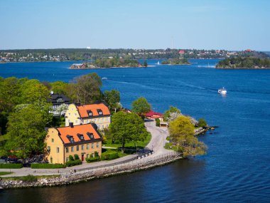 Stockholm Takımadaları 'ndaki geleneksel İsveç evlerinin yüksek perspektifi İsveç' in başkenti yakınlarındaki bir adada turuncu kırmızı çatılarla sarıya boyanmış..
