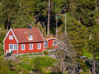 Stockholm Takımadası 'nın ormanlık bölgesinde geleneksel kırmızı boyalı kulübe seti. Bu evlerin çoğu İsveçliler tarafından hafta sonu tatili ve yaz tatili olarak kullanılıyor..