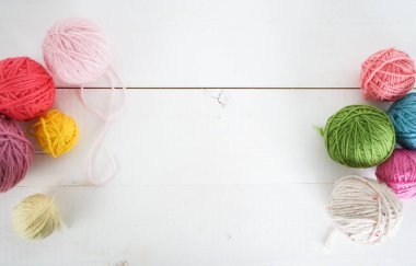 beyaz ahşap zemin üzerinde örgü kancalı çok renkli yün toplar, sarı, pembe, yeşil, kırmızı, metin arkaplanı için boşluk