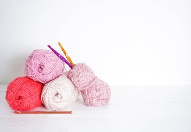 beyaz ahşap zemin üzerinde örgü kancalı çok renkli yün toplar, gri, pembe, gül