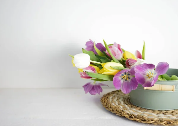 yellow, pink and purple tulips on white wooden ground with space for text