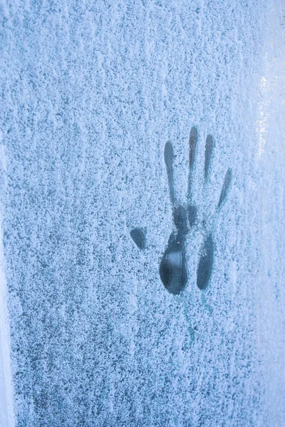 A palm print on a frozen window. Natural winter background.