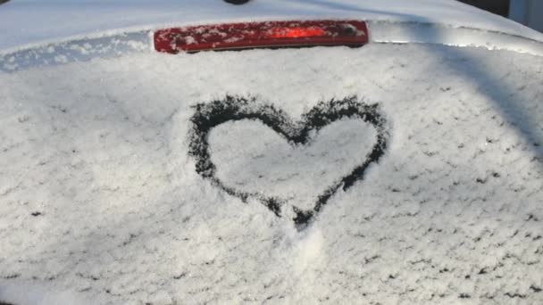 Καρδιά Ζωγραφισμένη Στο Χιόνι Στο Πίσω Παράθυρο Ενός Αυτοκινήτου Κοντινό — Αρχείο Βίντεο