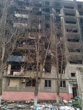 Savaş bölgesinde yanmış, yüksek katlı bir bina. Yerleşim bölgelerinde savaş, kırık camlar ve yanmış daireler