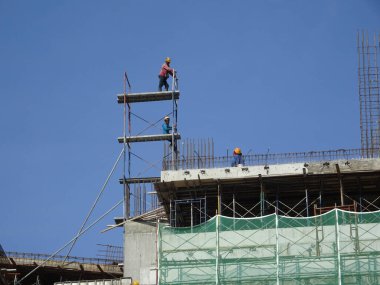 JOHOR, MALAYSIA - EPTEMBER 05, 2016: Emniyet kemeri ve yeterli güvenlik donanımı giyen inşaat işçileri ve yüksek seviyede çalışırken iskeleye tırmanıyorlar. 
