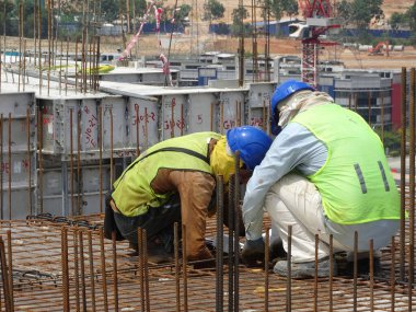 KUALA LUMPUR, MALAYSIA - 26 AĞUSTOS 2017: İnşaat işçileri inşaat alanında yer çeliği takviye çubuğu üretiyorlar. 