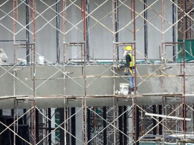 SELANGOR, MALAYSIA - 26 AĞUSTOS 2017: Yüksek seviyede sıva yaparken emniyet kemeri ve yeterli güvenlik donanımı giyen inşaat işçileri.  