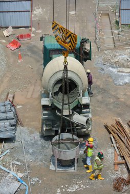SELANGOR, MALAYSIA - 07 Mart 2016: Beton karıştırıcı kamyon sıvı beton dökülüyor ve inşaat alanında kule vinç kova.  
