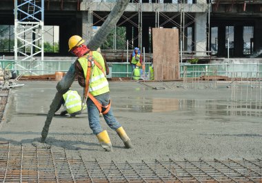 SELANGOR, MALAYSIA MAYIS 2014: Beton pompadan hortum taşıyan inşaat işçileri veya Selangor, Malezya 'daki inşaat sahasında yapılan beton çalışmalar sırasında fil hortumu olarak da bilinir.