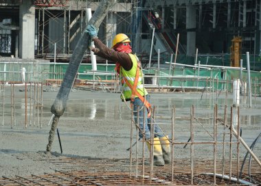 SELANGOR, MALAYSIA MAYIS 2014: Beton pompadan hortum taşıyan inşaat işçileri veya Selangor, Malezya 'daki inşaat sahasında yapılan beton çalışmalar sırasında fil hortumu olarak da bilinir.