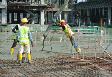 SELANGOR, MALAYSIA MAYIS 2014: Beton pompadan hortum taşıyan inşaat işçileri veya Selangor, Malezya 'daki inşaat sahasında yapılan beton çalışmalar sırasında fil hortumu olarak da bilinir.