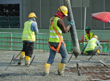 SELANGOR, MALAYSIA MAYIS 2014: Beton pompadan hortum taşıyan inşaat işçileri veya Selangor, Malezya 'daki inşaat sahasında yapılan beton çalışmalar sırasında fil hortumu olarak da bilinir.