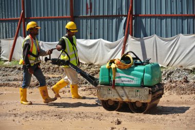 SELANGOR, MALAYSIA -NOVEMBER 25, 2015: Construction workers using baby roller compactor to compact soil at the construction site.