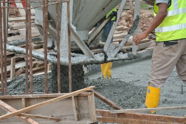 JOHOR, MALAYSIA - 12 Mayıs 2016: İnşaat alanındaki inşaat alanında zemine beton kova döken bir grup inşaat işçisi.  