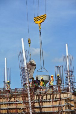 JOHOR, MALAYSIA - 12 Mayıs 2016: İnşaat alanındaki inşaat alanında zemine beton kova döken bir grup inşaat işçisi.  