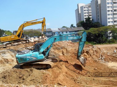 MELAKA, MALAYSIA - 6 Mart 2021: İnşaat alanında kazıcı makine. İnşaat alanında toprak ve diğer malzemelerin çıkarılması ve kaldırılması için kullanılır. Hidrolik bir kovayla güçlendirilmiş..  
